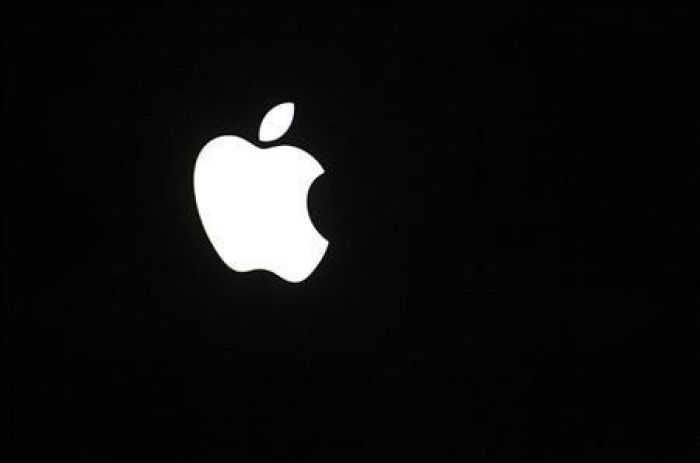 The apple logo glows on the back of a Macbook Pro. 