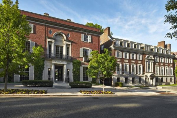 Historic brick building with large windows, surrounded by greenery and a well-maintained landscape.
