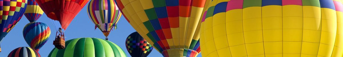Colorful hot air balloons fill the sky against a clear blue backdrop, showcasing various designs and patterns.