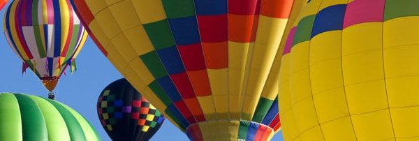 Colorful hot air balloons fill the sky against a clear blue backdrop, showcasing various designs and patterns.