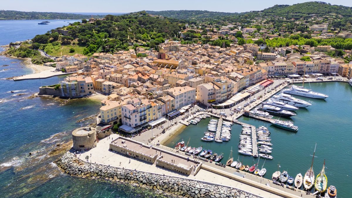 Aerial view of the scenic coastline and vibrant harbor of Saint-Tropez, showcasing charming architecture and luxurious yachts.
