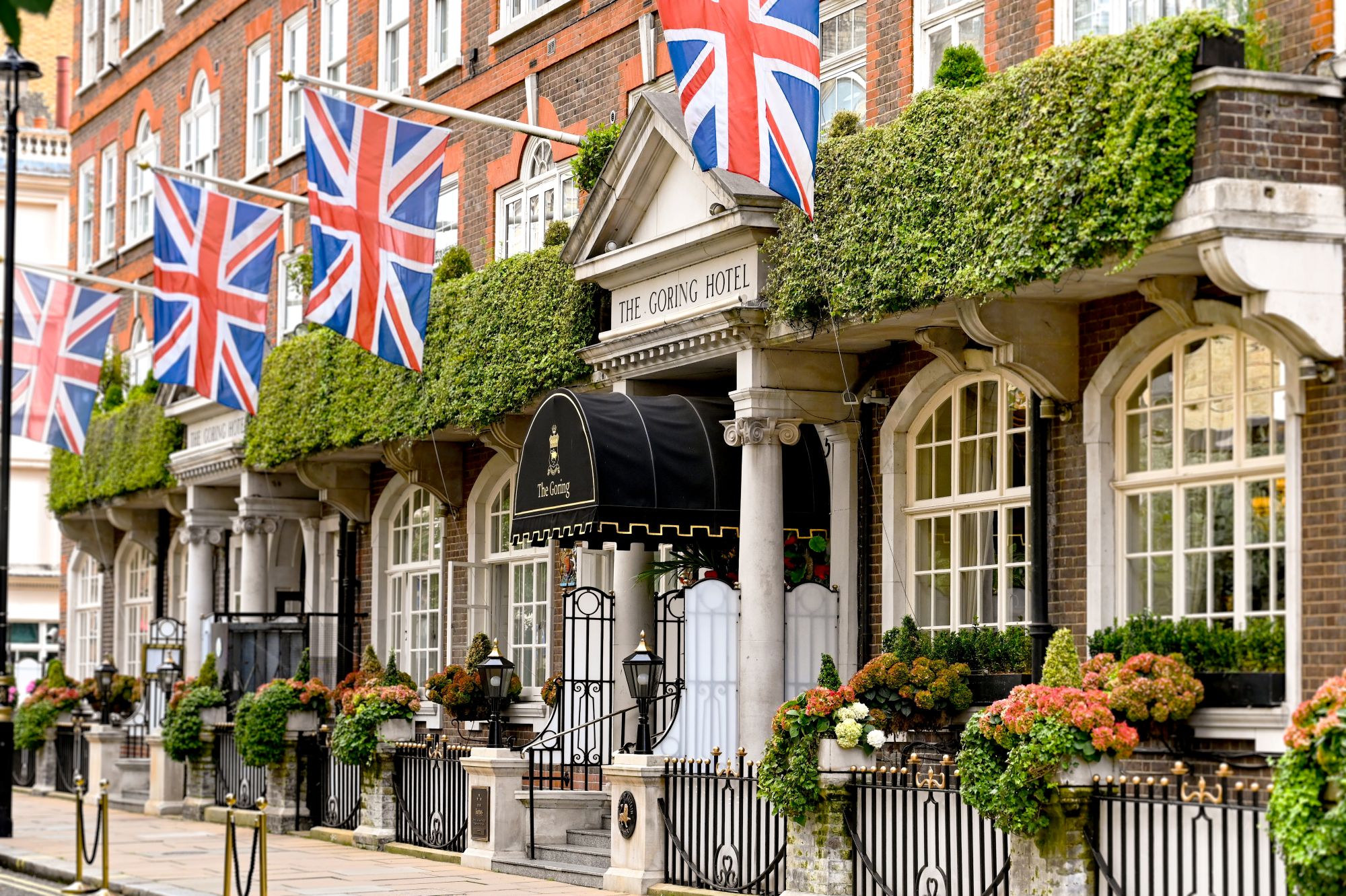 The Goring Hotel entrance adorned with British flags and lush greenery, showcasing London’s festive charm.