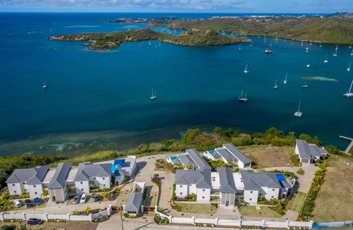 Luxury residences at The Point Private Residence Club overlooking a scenic bay with boats anchored in Grenada.