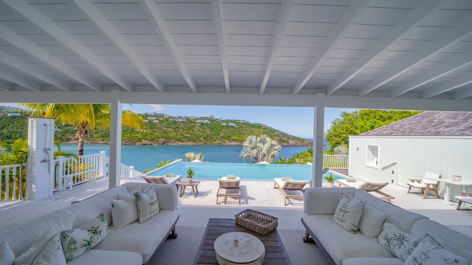 Outdoor lounge area with white furnishings and a stunning view of the pool and coastline at Villa Captiva, St. Barth.