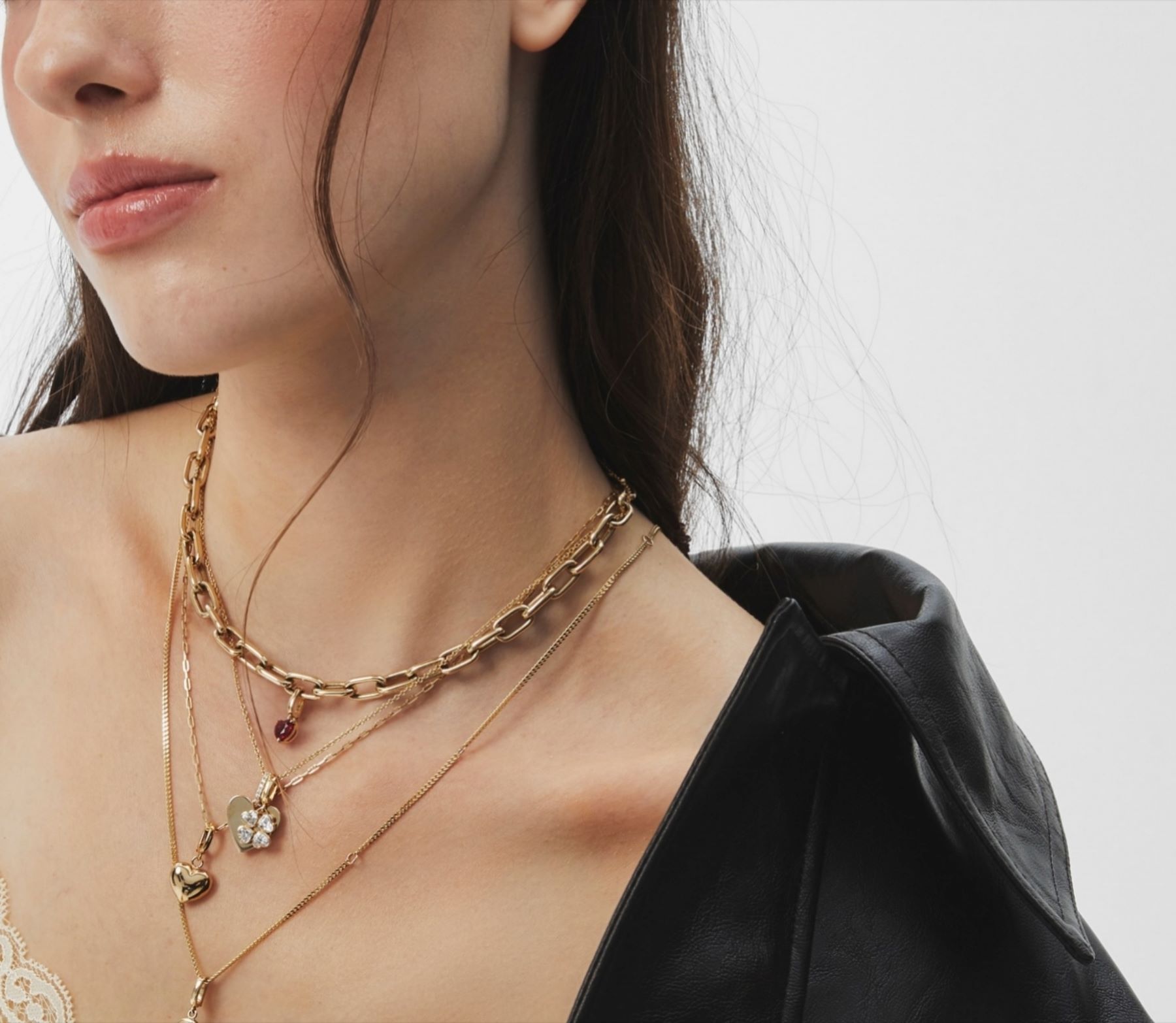 Model wearing layered gold necklaces against a minimalistic background, showcasing a stylish and elegant look.