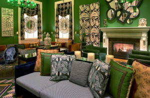 Luxurious living room featuring green walls, eclectic decor, various patterned cushions, and a cozy fireplace.