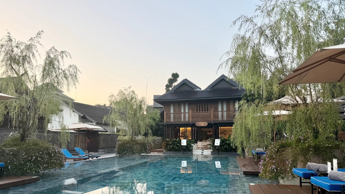 A serene pool surrounded by lush greenery and elegant architecture at The Aleenta Retreat in Chiang Mai.
