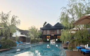 A serene pool surrounded by lush greenery and elegant architecture at The Aleenta Retreat in Chiang Mai.