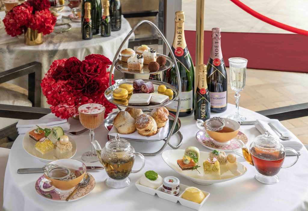 Glamorous afternoon tea setup with scones, pastries, tea, and champagne, adorned with red flowers for the Golden Globes theme.