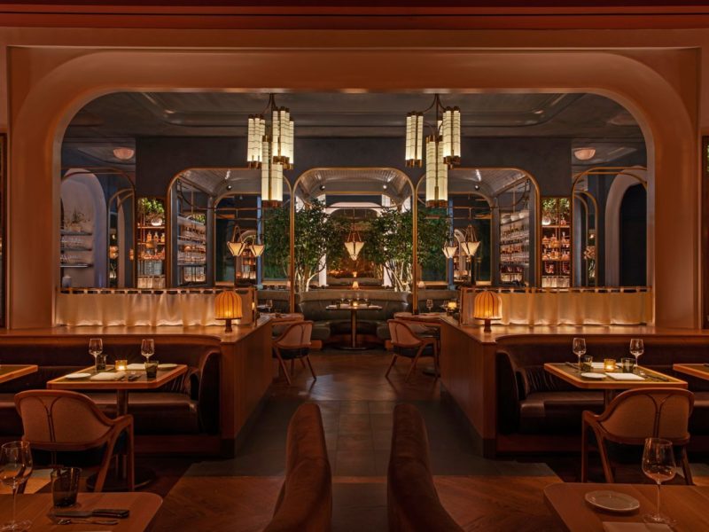 Elegant interior of Bourbon Steak New York featuring plush seating, ambient lighting, and lush greenery.