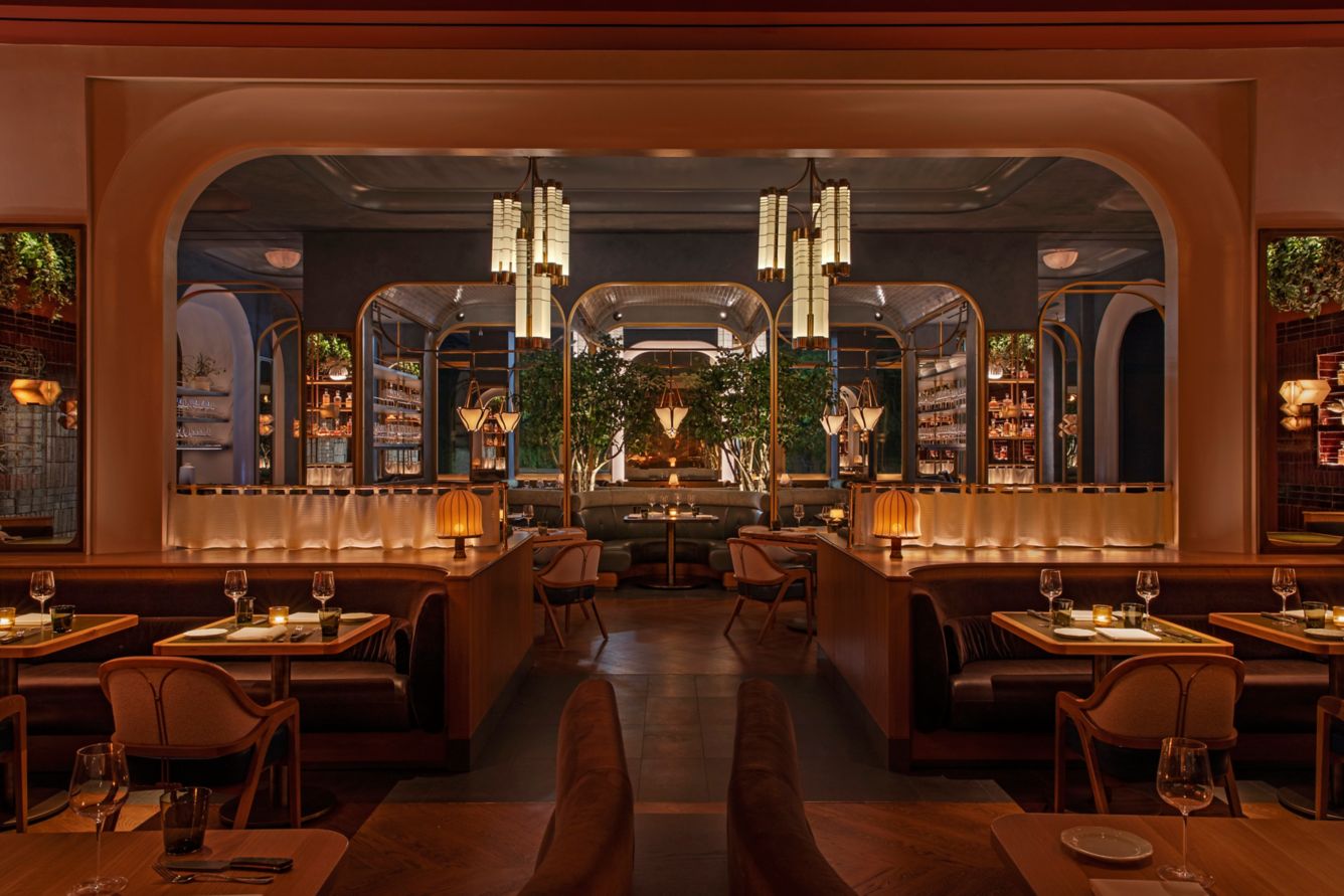 Elegant interior of Bourbon Steak New York featuring plush seating, ambient lighting, and lush greenery.