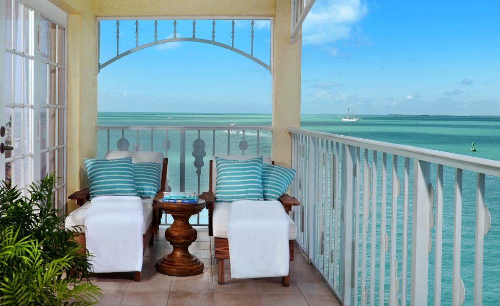Balcony view with two striped chairs, a small table, and a serene ocean backdrop at Ocean Key Resort & Spa.