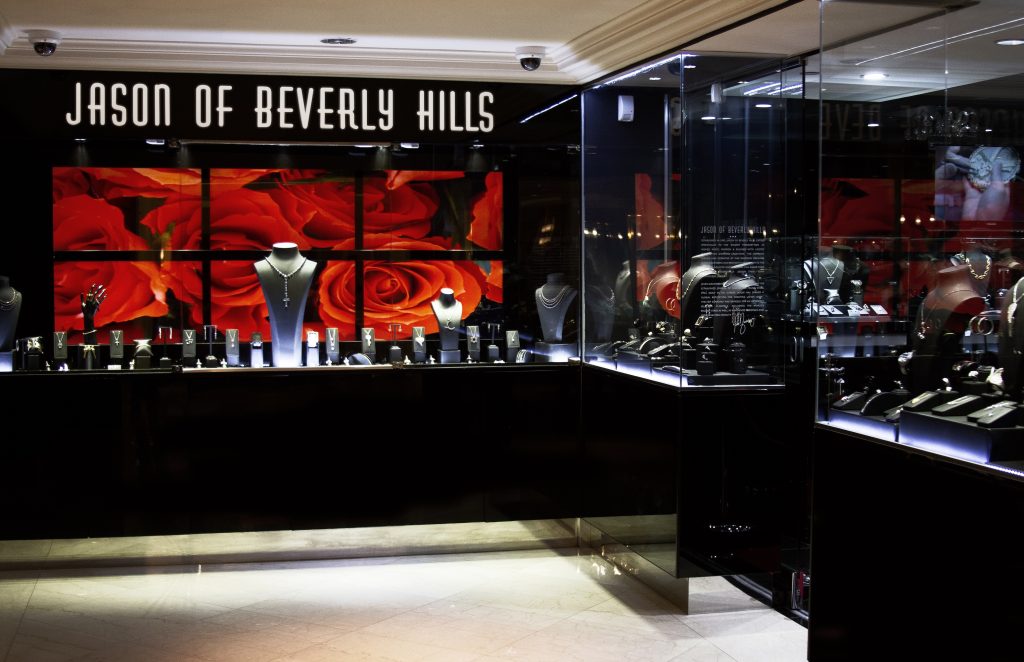 Luxurious jewelry displays by Jason of Beverly Hills, featuring elegant pieces set against a backdrop of vibrant red roses.
