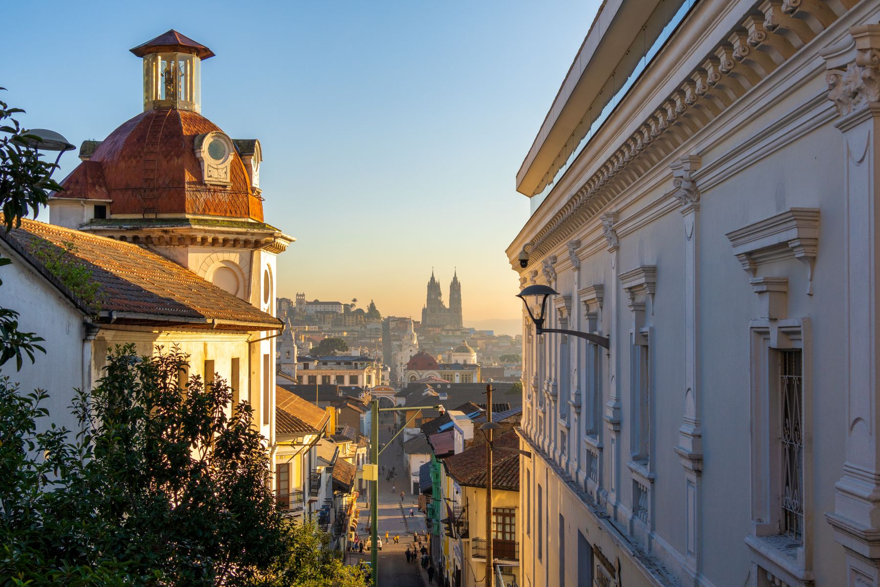 Scenic view of a historic neighborhood in Latin America at sunrise, showcasing architecture and a distant church steeple.