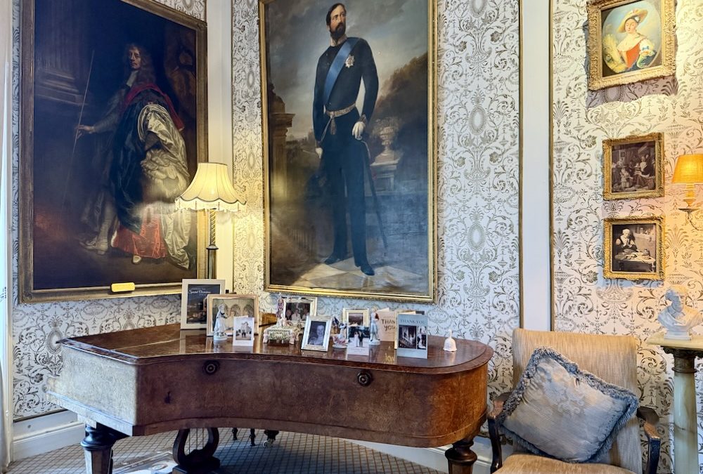 A lavish room at Cabra Castle featuring ornate paintings, a vintage table adorned with photographs, and elegant decor.