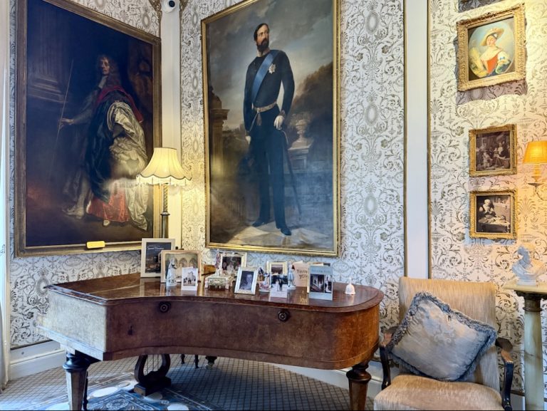 A lavish room at Cabra Castle featuring ornate paintings, a vintage table adorned with photographs, and elegant decor.