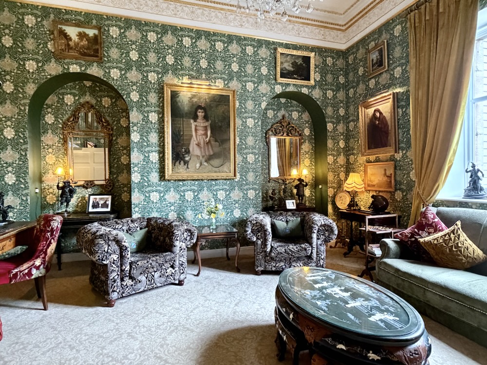 Luxurious sitting area in Cabra Castle featuring ornate decor, vintage paintings, and plush seating against a floral backdrop.
