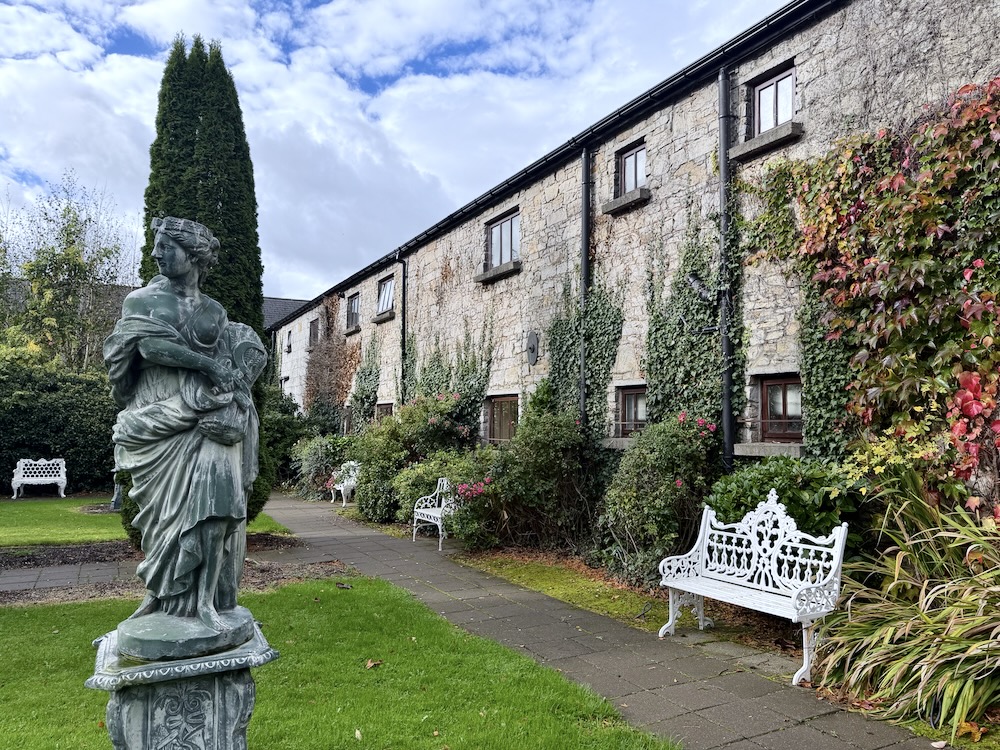 A statue and manicured gardens enhance the charming exterior of Cabra Castle in Ireland, showcasing its historic appeal.