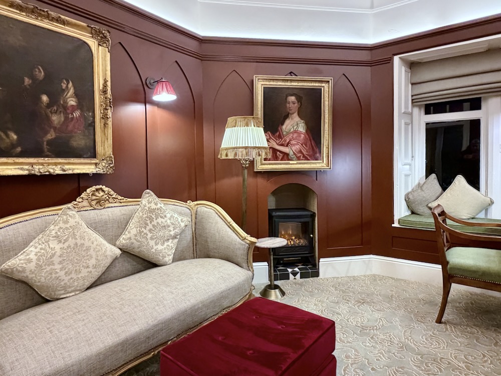 Cozy sitting area in Cabra Castle featuring antique furniture, warm lighting, and classic artwork on the walls.