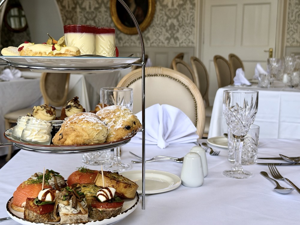 A tiered stand holds an assortment of pastries, scones, and savory dishes set in an elegant dining room.