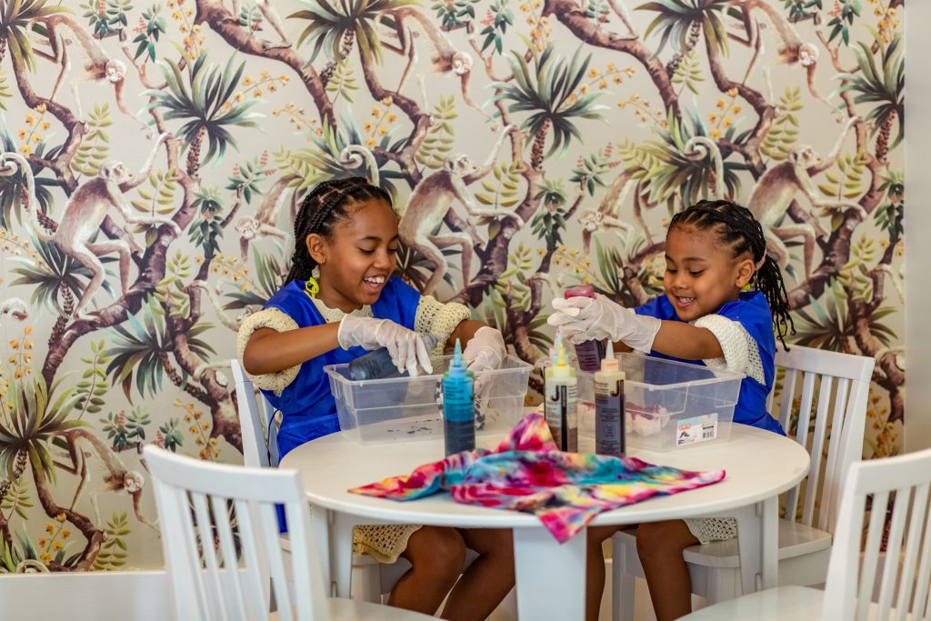 Two children enjoy a creative activity at the Four Seasons Resort Nevis, dyeing fabric with vibrant colors.