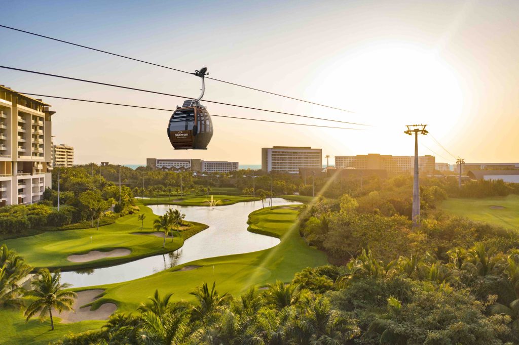 Gondola above golf course and resort, set against a sunset in VidantaWorld Nuevo Vallarta.