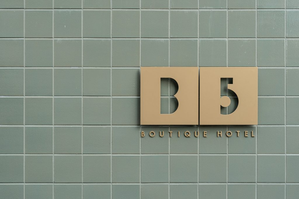 B5 Boutique Hotel sign displayed on a tiled wall, featuring modern design elements and a soft color palette.