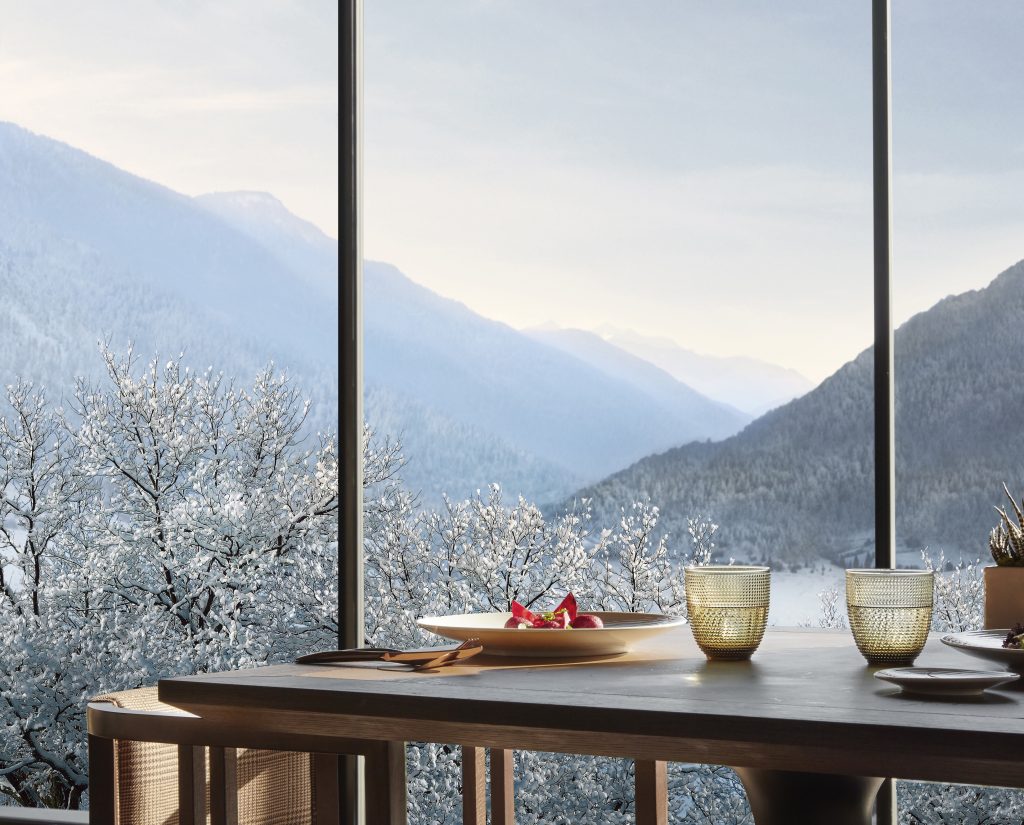 A cozy dining setup overlooking snow-covered mountains and trees at Lefay SPA Dolomiti.