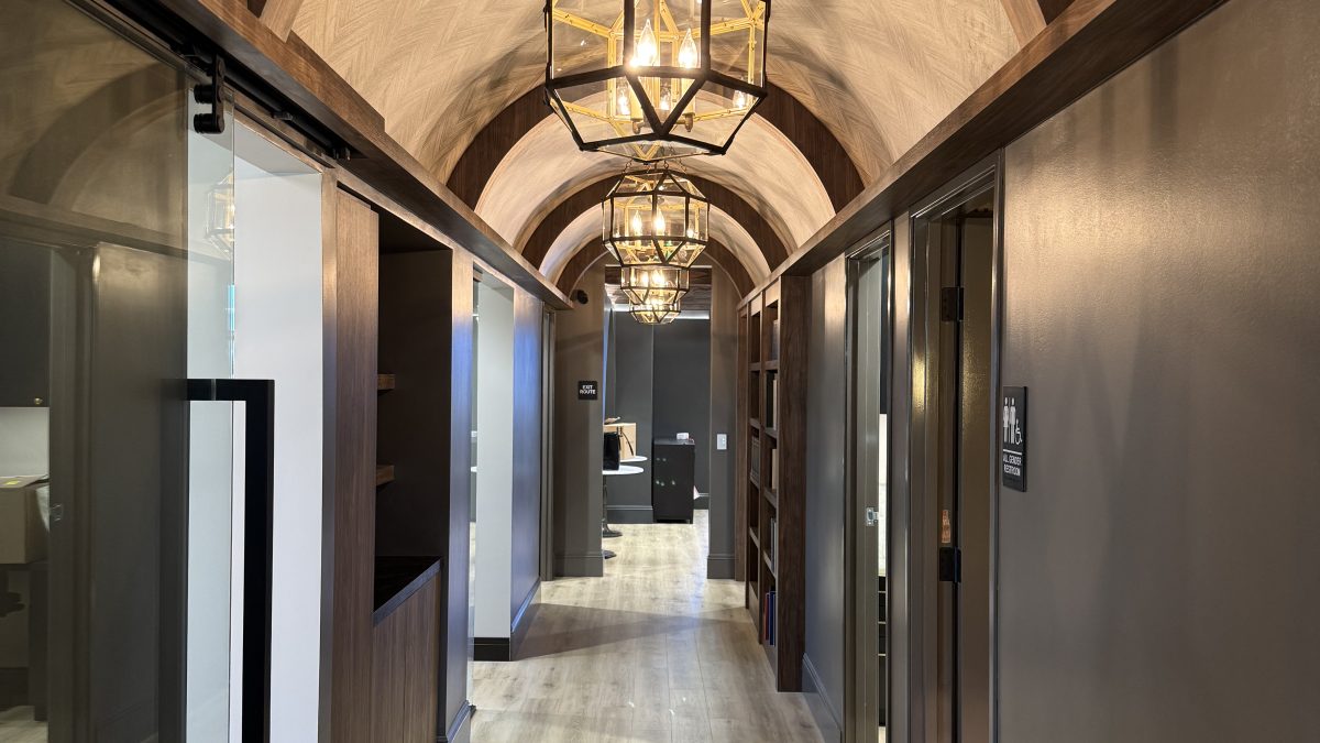 Elegant hallway of Dr. Tyler Hales' speakeasy-inspired aesthetic practice, featuring arched ceilings and stylish lighting fixtures.
