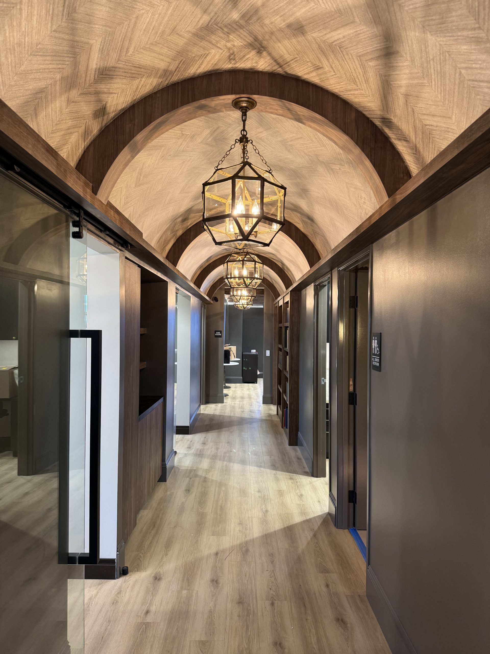 Elegant hallway of Dr. Tyler Hales' speakeasy-inspired aesthetic practice, featuring arched ceilings and stylish lighting fixtures.
