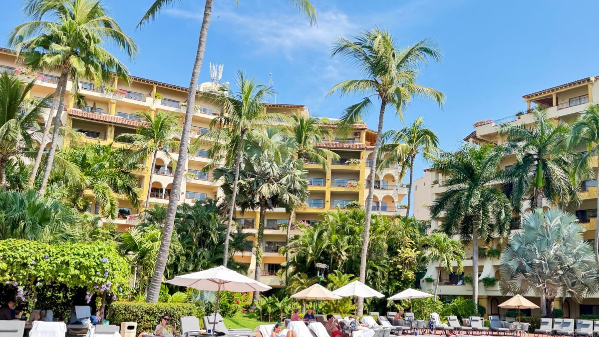 Resort pool surrounded by palm trees, lounge chairs, and vibrant greenery at the Velas Resorts in Mexico.