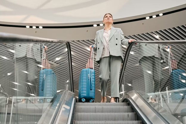 Businesswoman with luggage standing on an escalator, contemplating the impact of living abroad on her career.