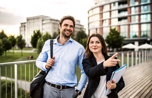 A man and a woman walk together, smiling, against a backdrop of buildings and greenery, discussing their career paths.