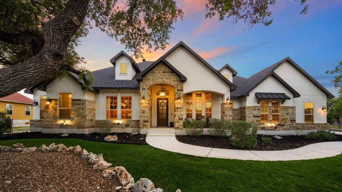 Luxury home exterior showcasing stone accents, landscaped yard, and warm lighting at sunset, inviting major renovation discussions.