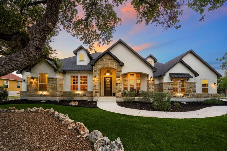 Luxury home exterior showcasing stone accents, landscaped yard, and warm lighting at sunset, inviting major renovation discussions.