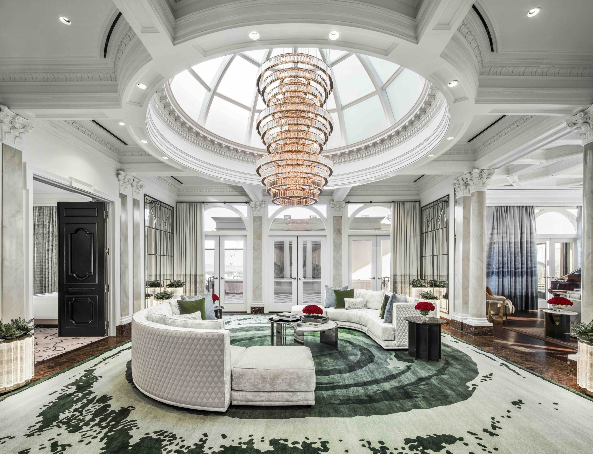 Luxurious atrium with a grand chandelier, elegant furnishings, and large windows offering natural light at Caesars Palace.