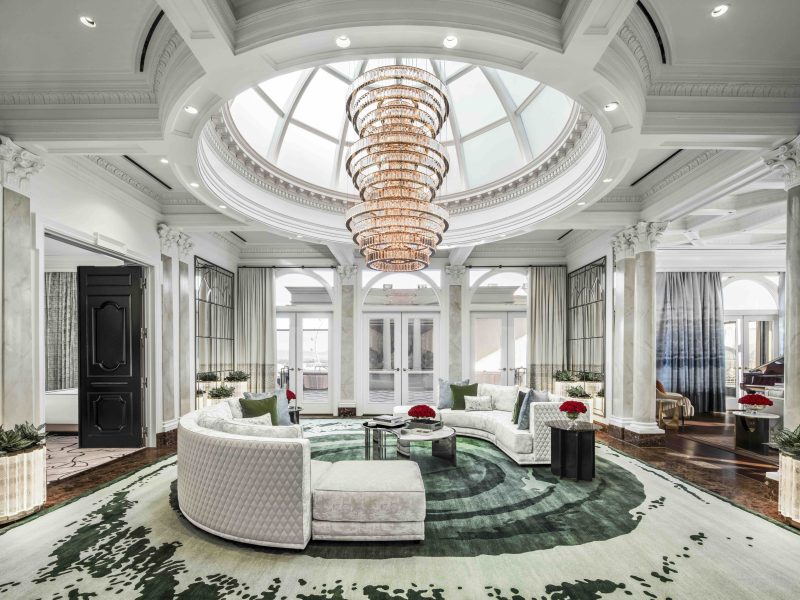 Luxurious atrium with a grand chandelier, elegant furnishings, and large windows offering natural light at Caesars Palace.