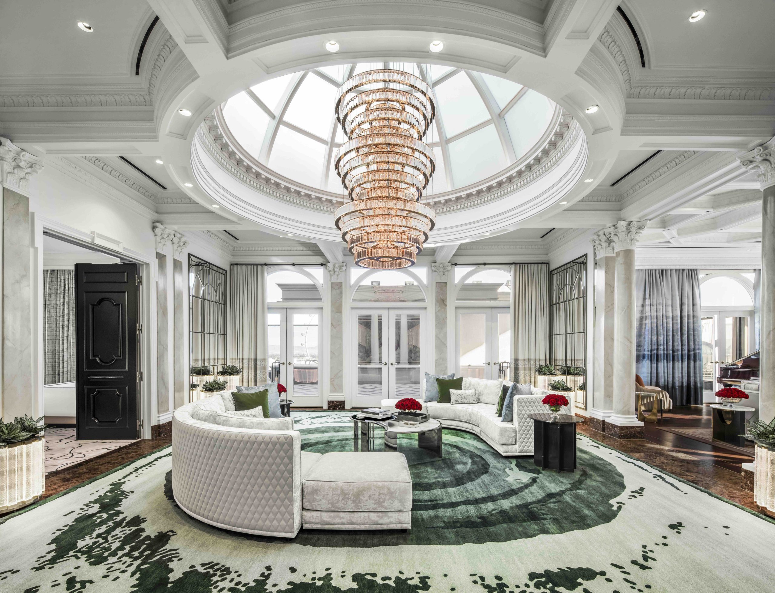 Luxurious atrium with a grand chandelier, elegant furnishings, and large windows offering natural light at Caesars Palace.
