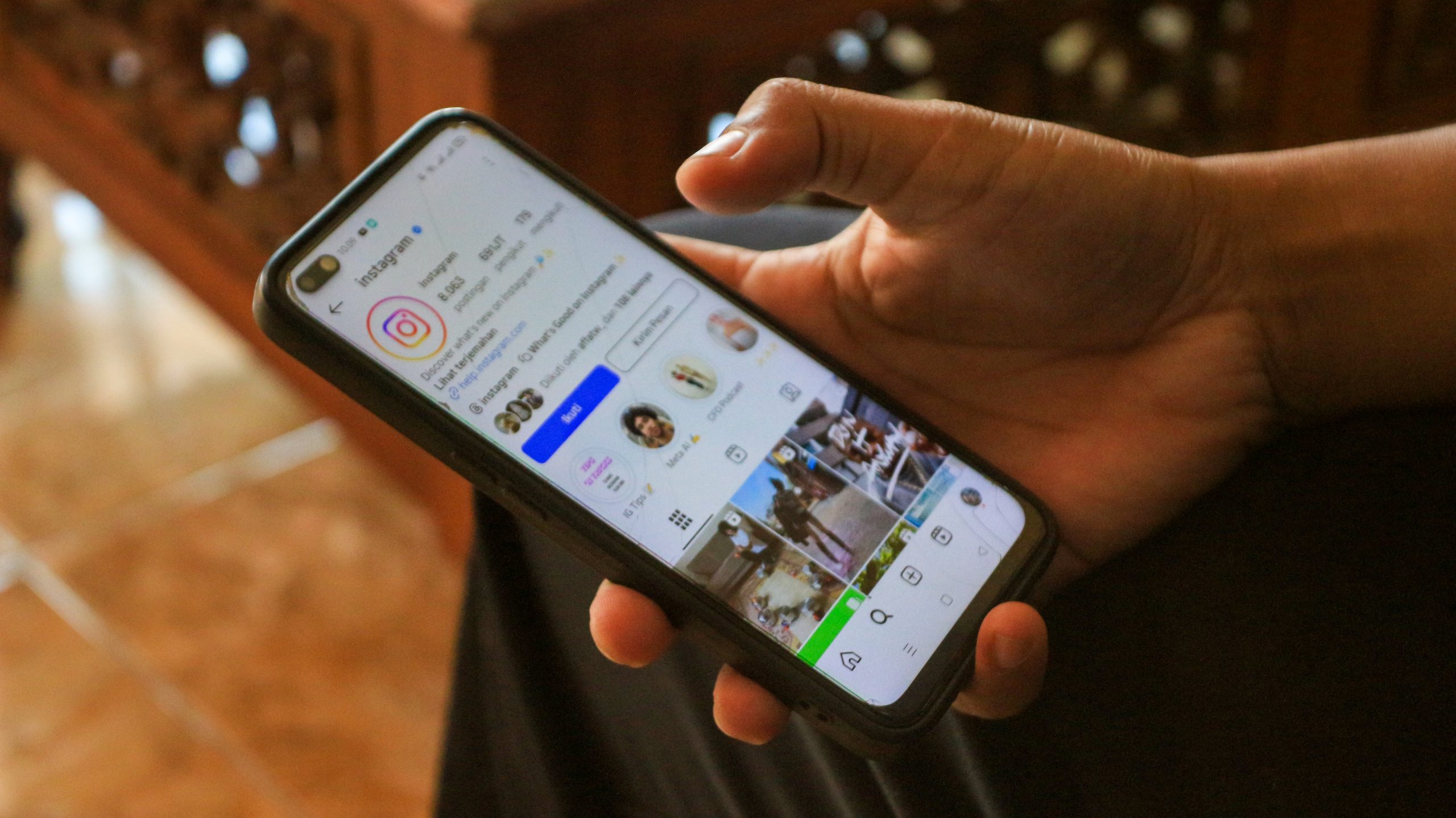A person using a smartphone displaying their Instagram profile and feed.