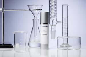 CielementsMD DNA Defense daily cream surrounded by laboratory glassware, emphasizing skincare science for UVA protection.