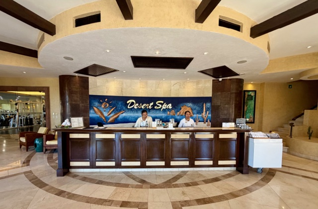 Desert Spa reception area with two staff members at the front desk and a vibrant mural in the background.