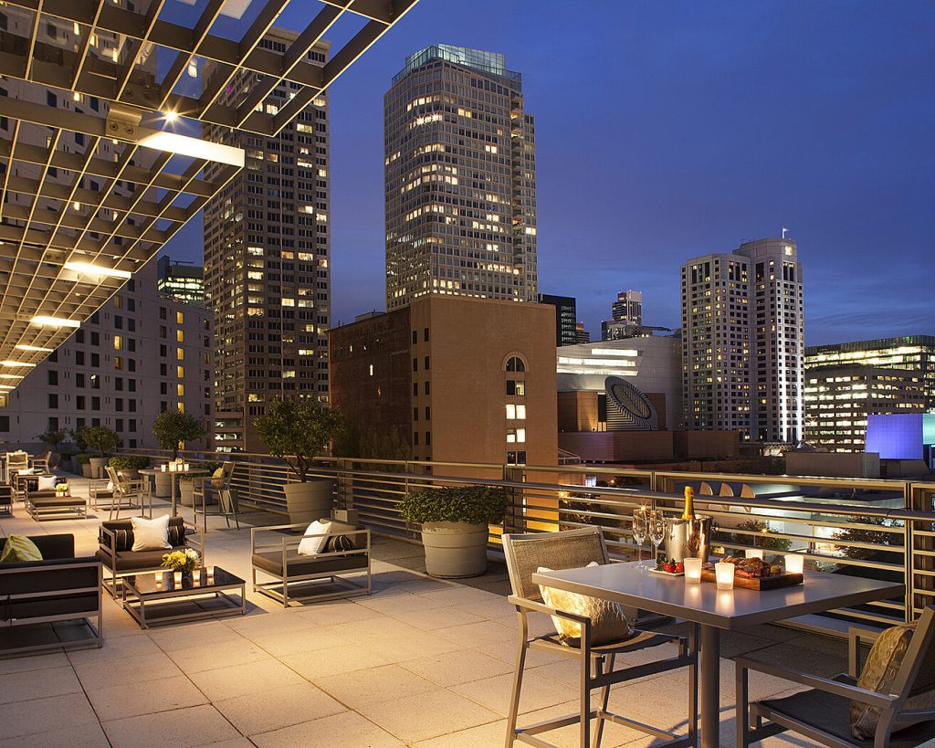 Rooftop terrace overlooking a city skyline, featuring outdoor seating and soft lighting, perfect for a Super Bowl stay.