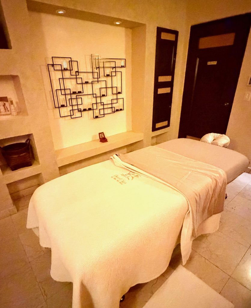 A tranquil spa treatment room featuring a massage table, soft lighting, and decorative wall art for relaxation.