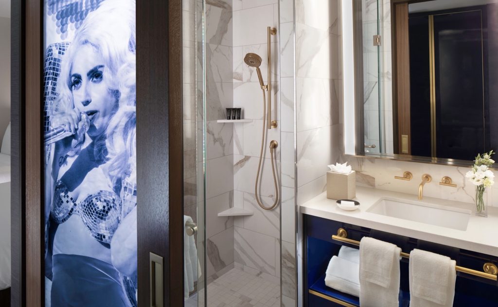 Luxurious bathroom at Hard Rock Hotel New York featuring a modern shower, gold fixtures, and a decorative mural.