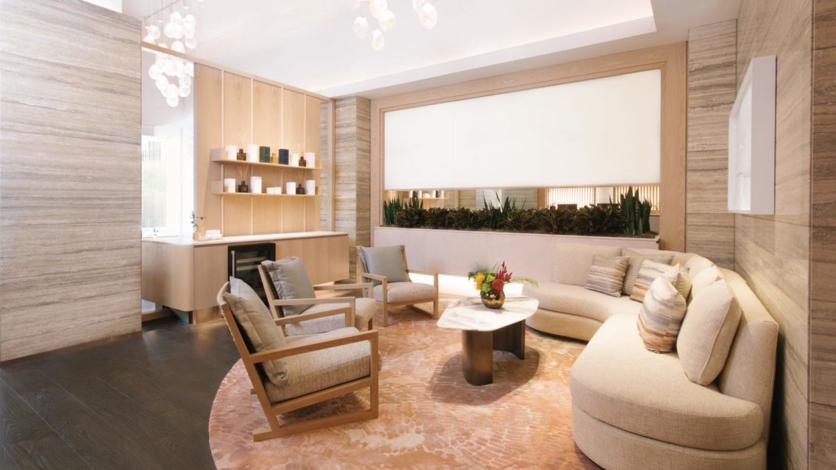 A modern, stylish lounge area featuring a curved sofa, wooden chairs, and a decorative rug, ideal for relaxation.