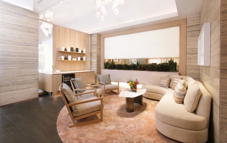 A modern, stylish lounge area featuring a curved sofa, wooden chairs, and a decorative rug, ideal for relaxation.