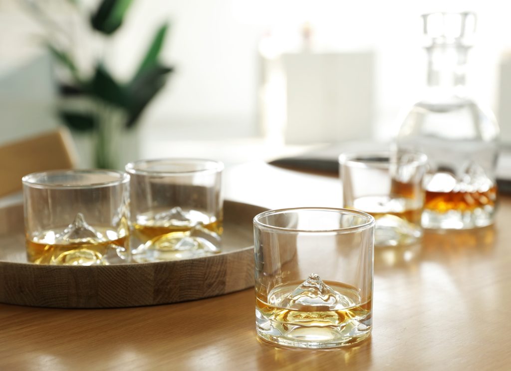 Whiskey glasses with amber liquid on a wooden tray, creating a cozy atmosphere for Valentine's Day.