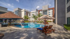 Luxurious pool area at Glee Nairobi with lounge chairs, umbrellas, and modern buildings in the background.