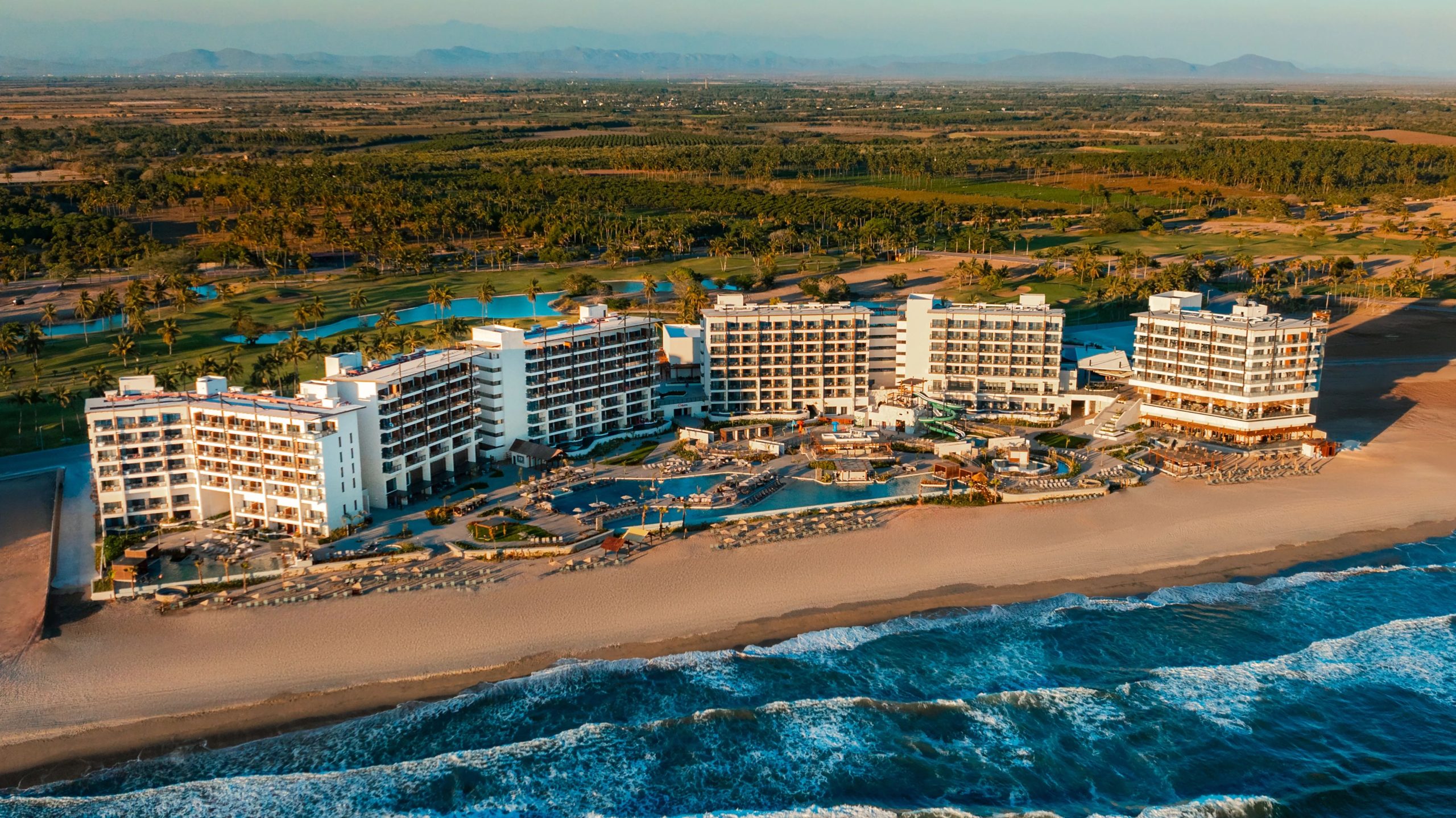 Dreams Estrella del Mar Mazatlán Golf & Spa Resort with beachfront, pools, and golf course surrounded by palm trees.