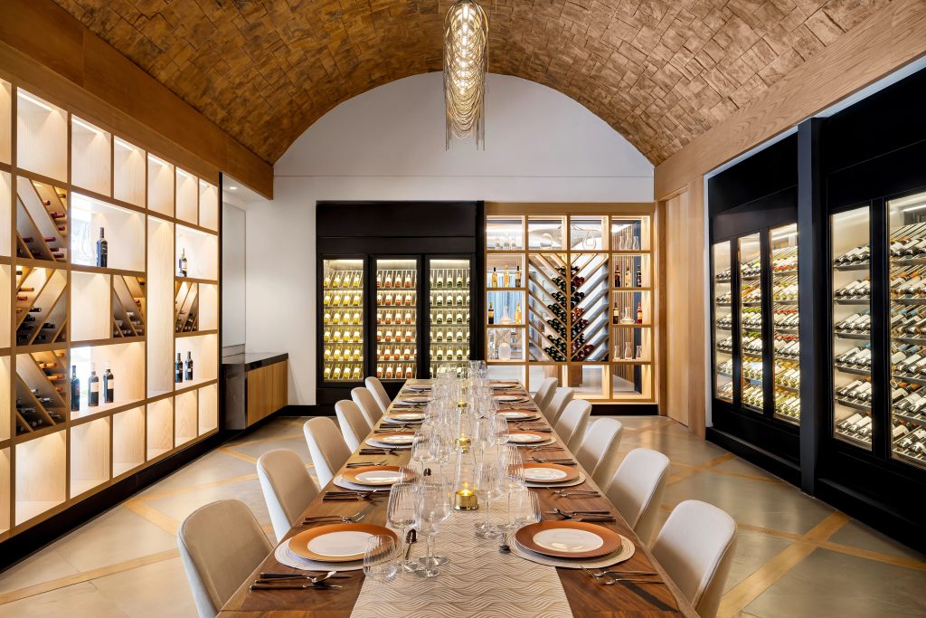 Elegant wine cellar featuring a long dining table, shelves of wine bottles, and modern decor at Dreams Estrella del Mar Mazatlán.